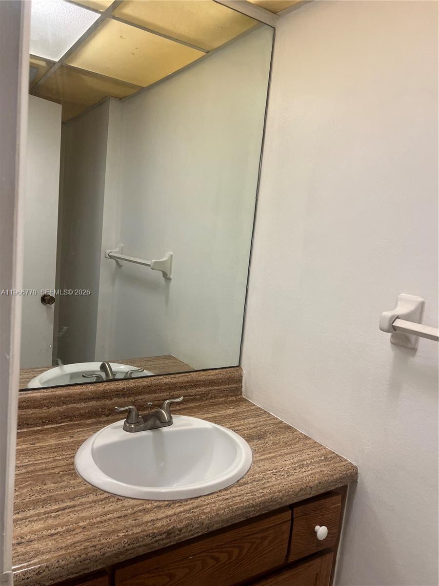 3690 Inverrary Drive, Unit 1K Lauderhill, FL 33319 - Photo 5 of 34 a bathroom with a granite countertop sink and a mirror