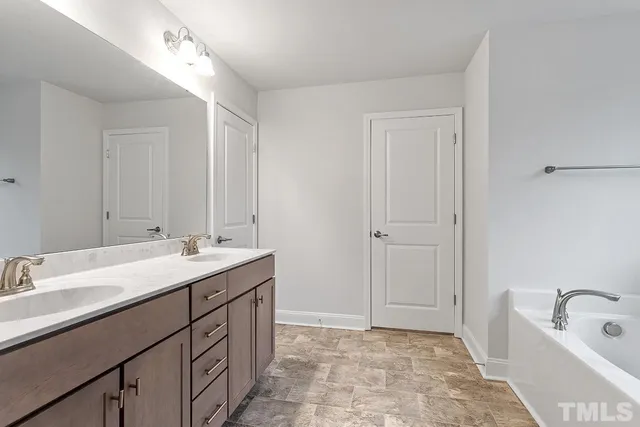 a bathroom with a tub sink double vanity and mirror