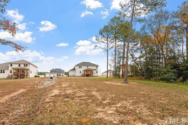 a view of a yard with a house and trees in the background