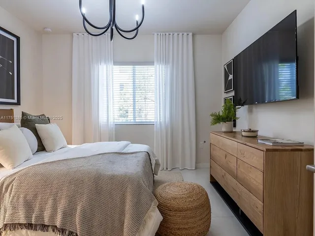 a bed room with a bed television and a window