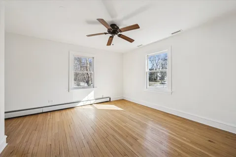 a view of empty room with wooden floor and fan