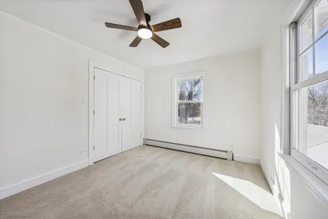 an empty room with windows and fan