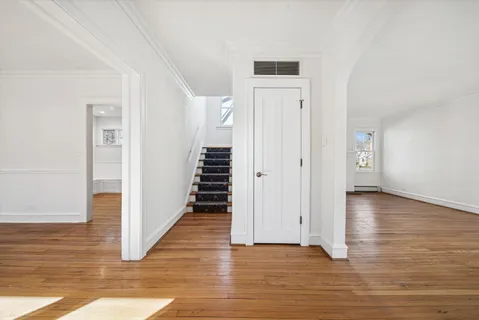 a view of a hallway with wooden floor and staircase