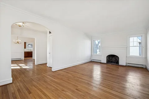 a view of empty room with wooden floor and fireplace