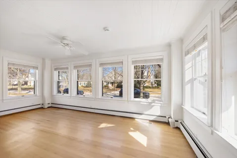 a view of an empty room with a window and wooden floor