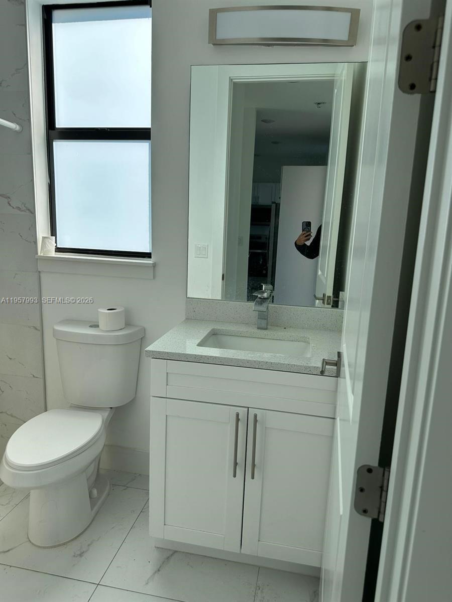 4660-4662 26th Street Southwest Lehigh Acres, FL 33973 - Photo 19 of 22 a bathroom with a toilet sink vanity and mirror