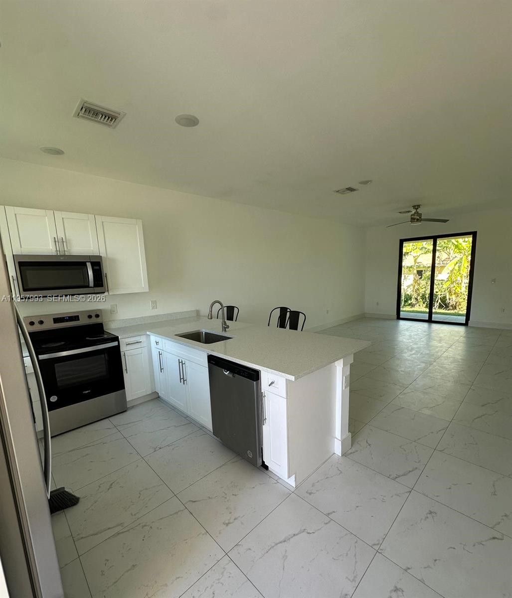 4660-4662 26th Street Southwest Lehigh Acres, FL 33973 - Photo 6 of 22 a kitchen with stainless steel appliances a stove a sink and a refrigerator