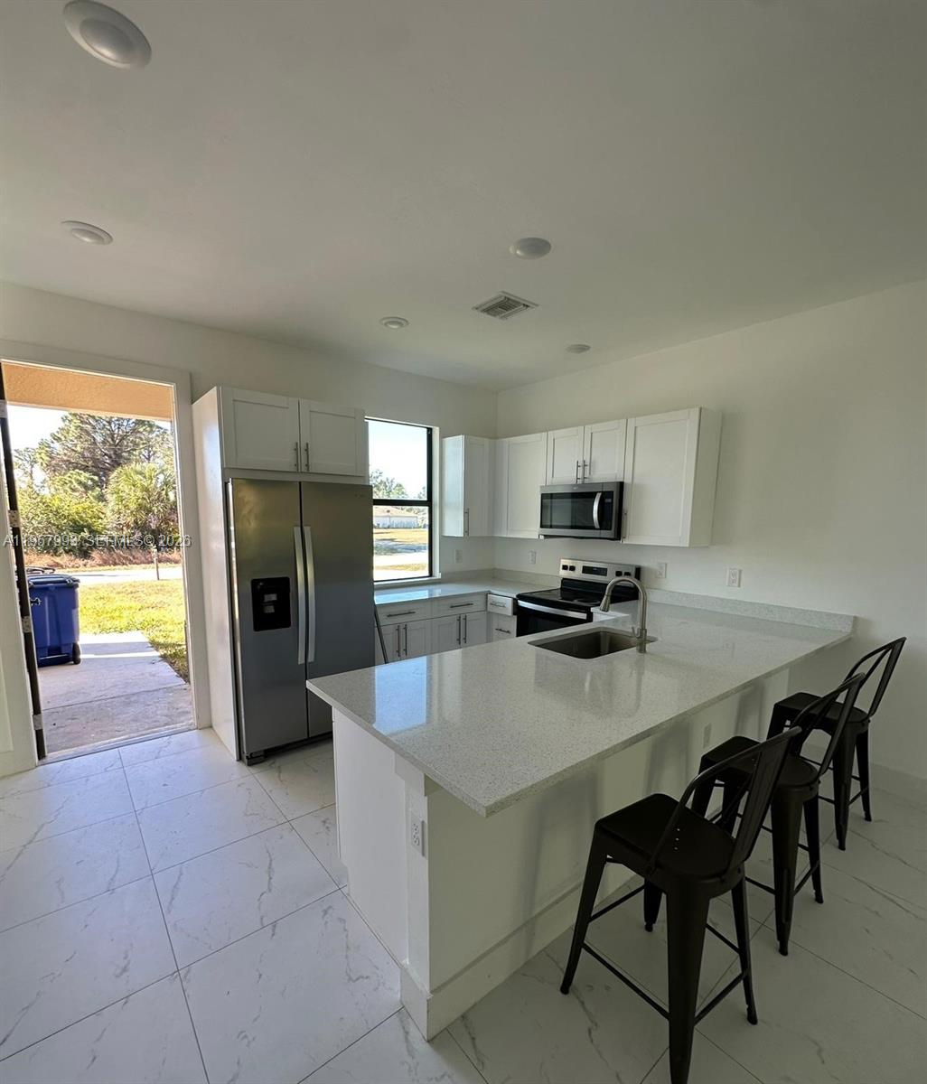 4660-4662 26th Street Southwest Lehigh Acres, FL 33973 - Photo 7 of 22 a large kitchen with a table chairs and refrigerator