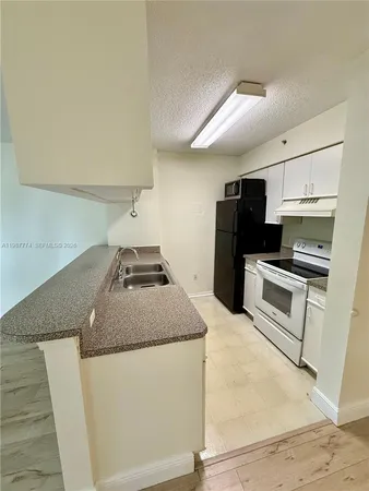 a kitchen with granite countertop a sink a stove and refrigerator