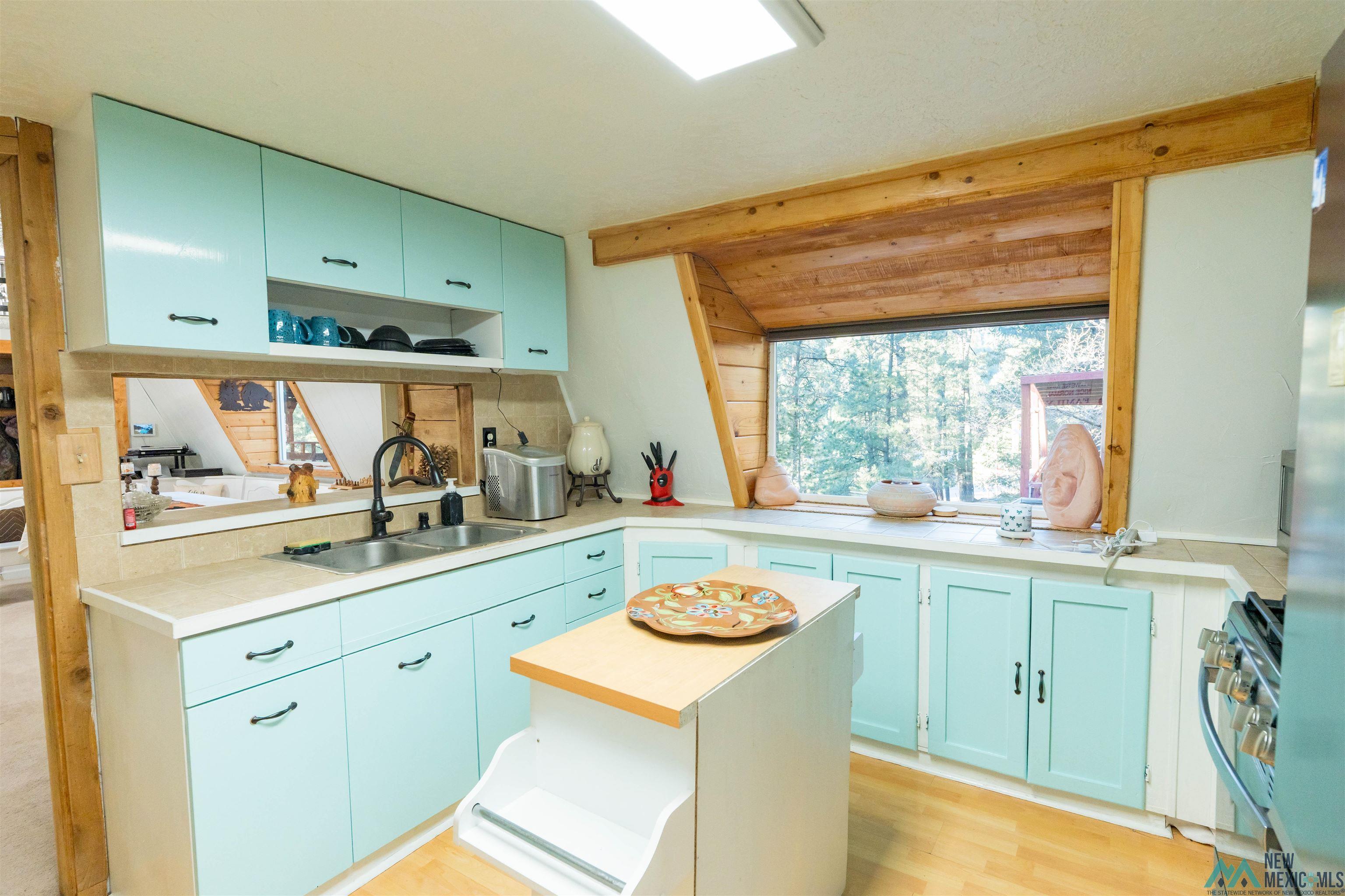 3 Wimsatt Road Cloudcroft, NM 88317 - Photo 13 of 41 Kitchen featuring appliances with stainless steel finishes, open shelves, blue cabinets, light wood-style floors, and a center island