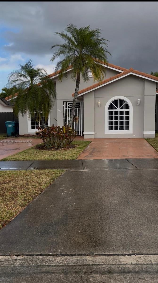 4911 Southwest 142nd Place Miami, FL 33175 - Photo 2 of 34 a front view of a house with a yard and garage