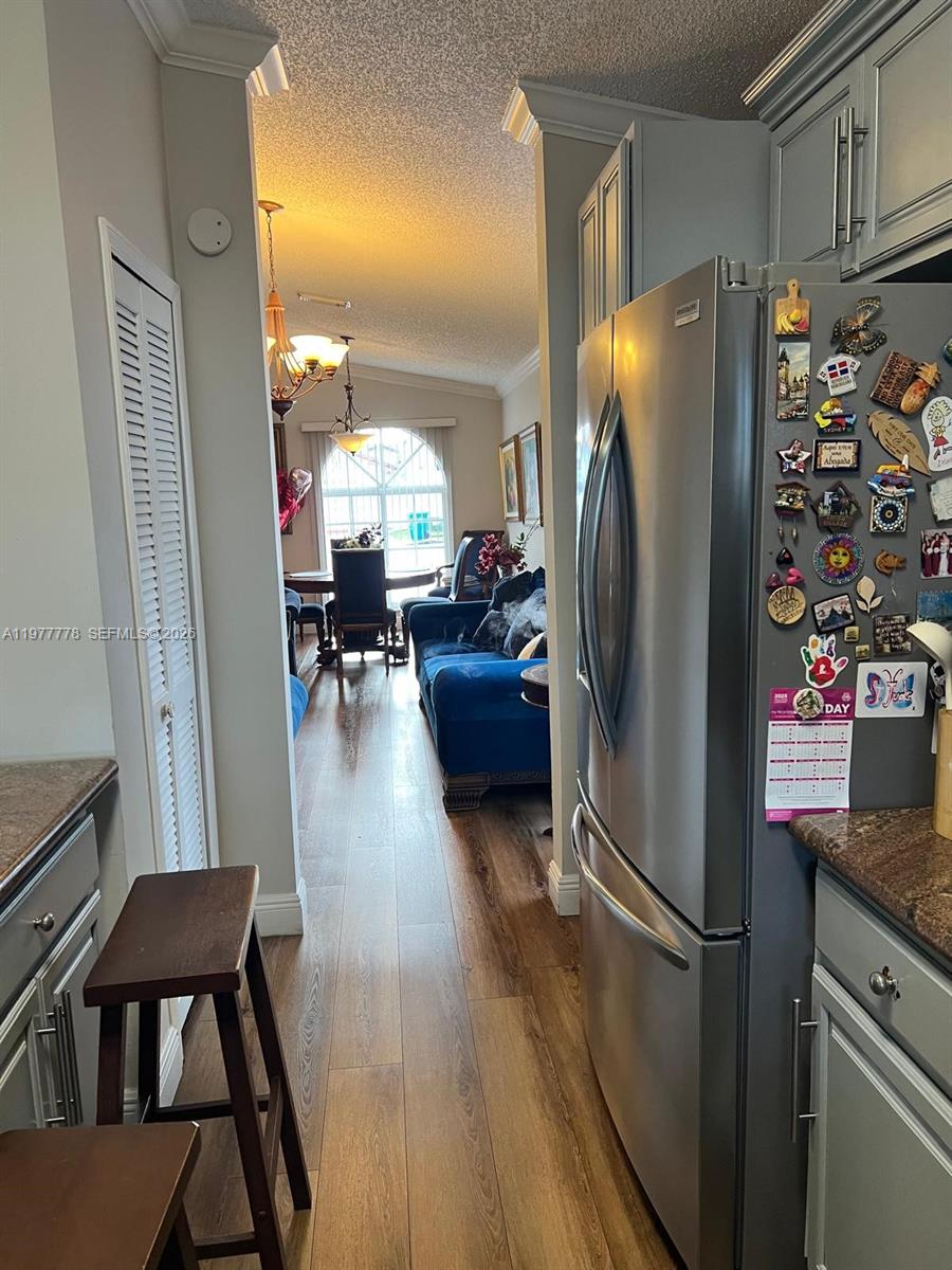 4911 Southwest 142nd Place Miami, FL 33175 - Photo 8 of 34 a kitchen with stainless steel appliances a refrigerator a stove a dining table and chairs with wooden floor