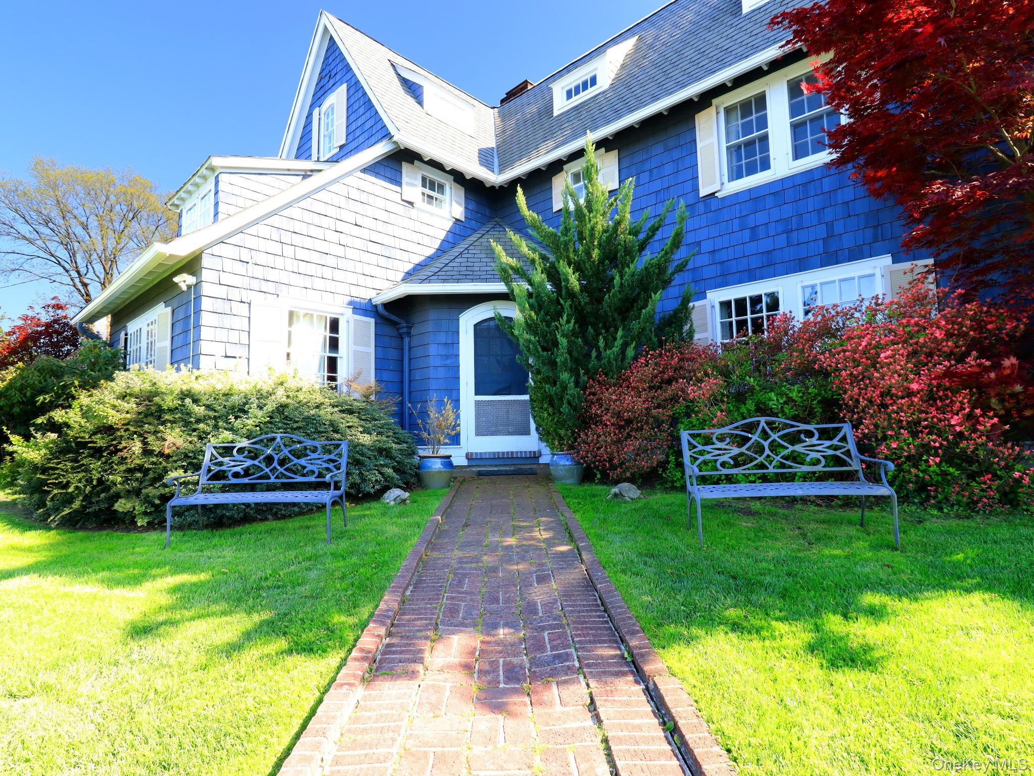 11-20 Shore Road Queens, NY 11363 - Photo 4 of 45 Blue shingle siding with white window shutters and trim, featuring a brick pathway leading to the arched entry door