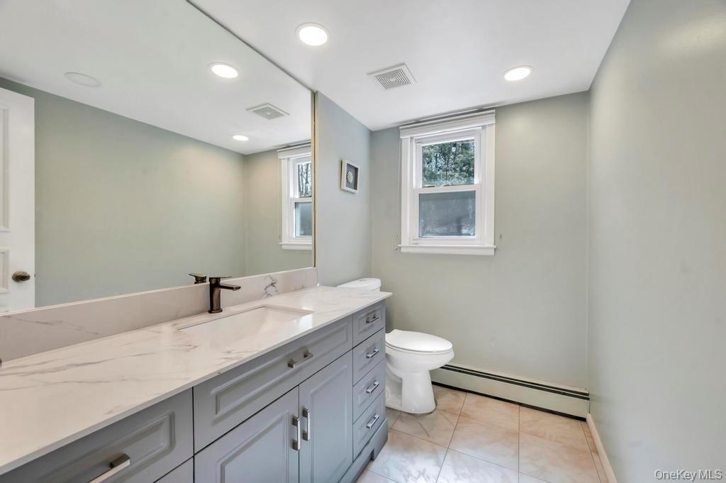 10 Hunting Hill Road Woodbury, NY 11797 - Photo 22 of 39 a bathroom with a granite countertop sink mirror vanity and a toilet