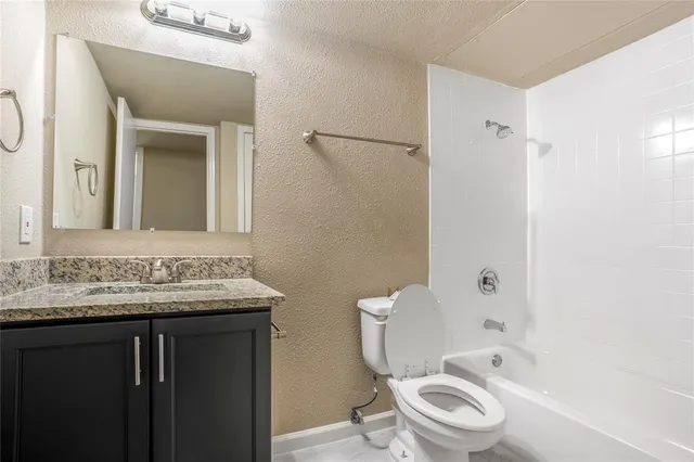 a bathroom with a granite countertop toilet sink and mirror