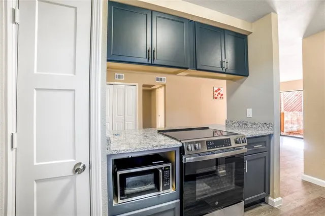 a kitchen with granite countertop cabinets stainless steel appliances and wooden floor