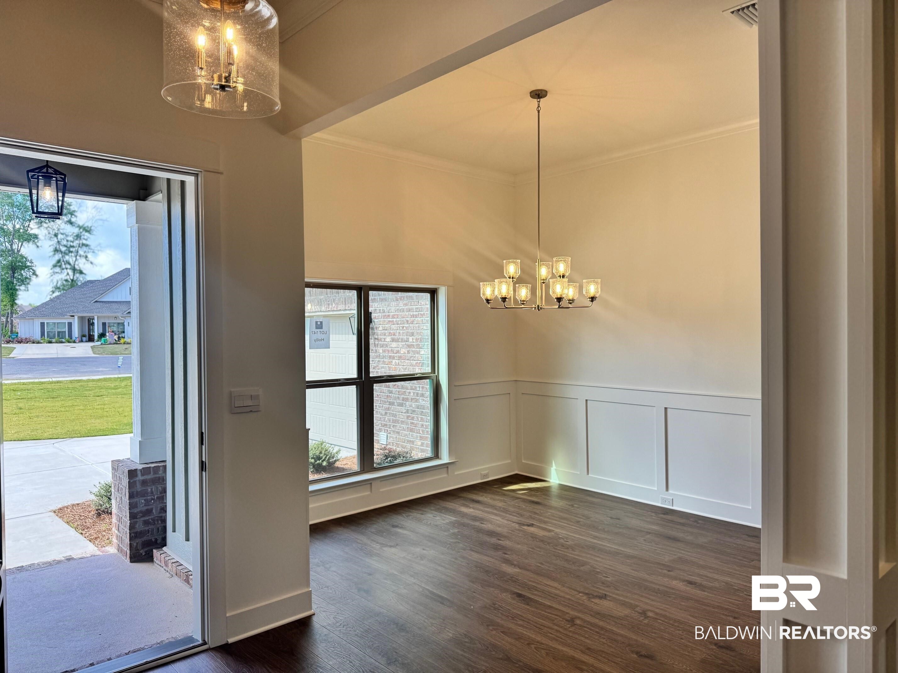 12248 Exbury Way Daphne, AL 36527 - Photo 2 of 63 Unfurnished dining area featuring suspended lighting, crown molding, plenty of natural light, dark wood-style flooring, and a decorative wall
