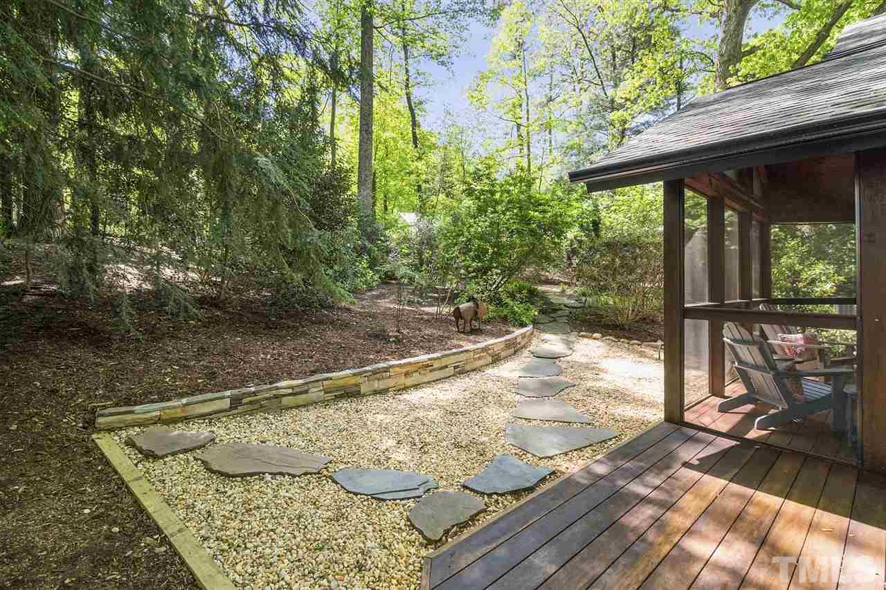 2908 Sandia Drive Raleigh, NC 27607 - Photo 7 of 29 Professional, modern landscape featuring stacked stone retaining wall, pebble drainage, low maintenance plantings and decking.