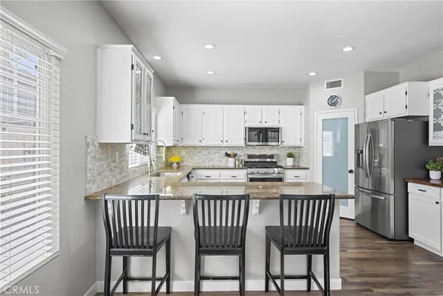 a kitchen with stainless steel appliances granite countertop a refrigerator a stove a sink a dining table and chairs