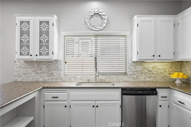 a kitchen with granite countertop white cabinets and window