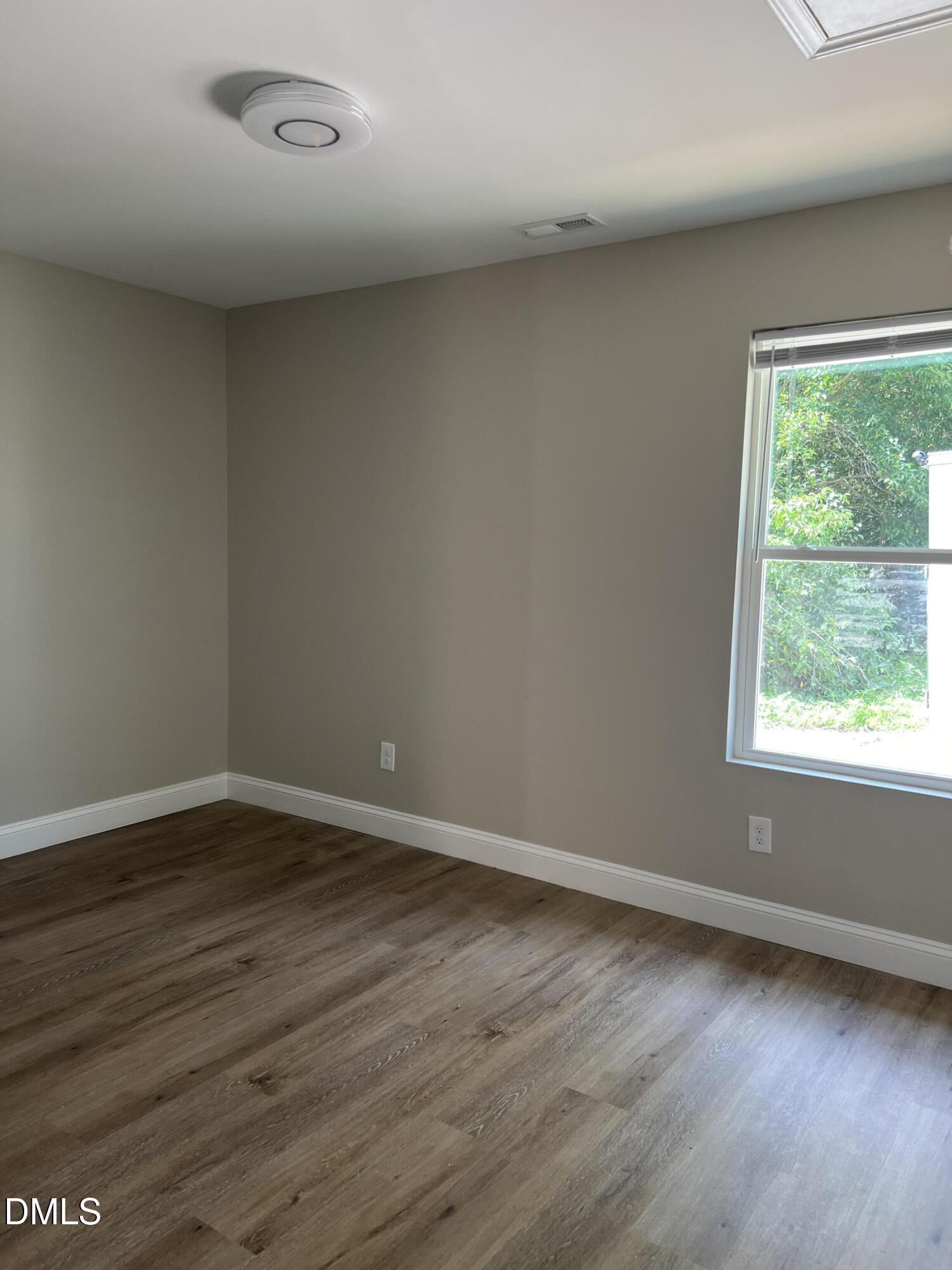 507 North Maple Street, Unit A Durham, NC 27703 - Photo 11 of 15 an empty room with wooden floor and windows