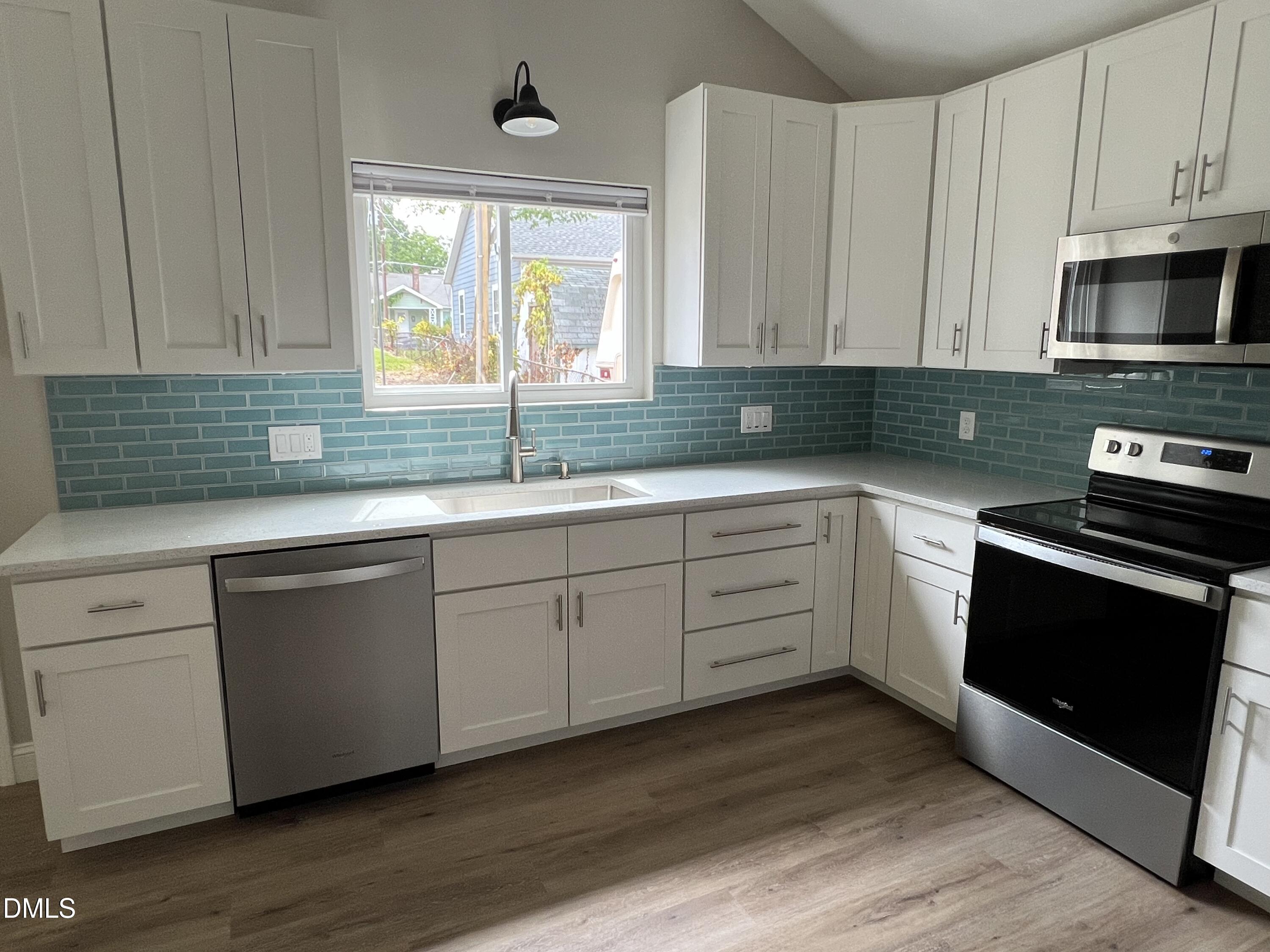 507 North Maple Street, Unit A Durham, NC 27703 - Photo 4 of 15 a kitchen with stainless steel appliances granite countertop a sink a stove a microwave a window and cabinets