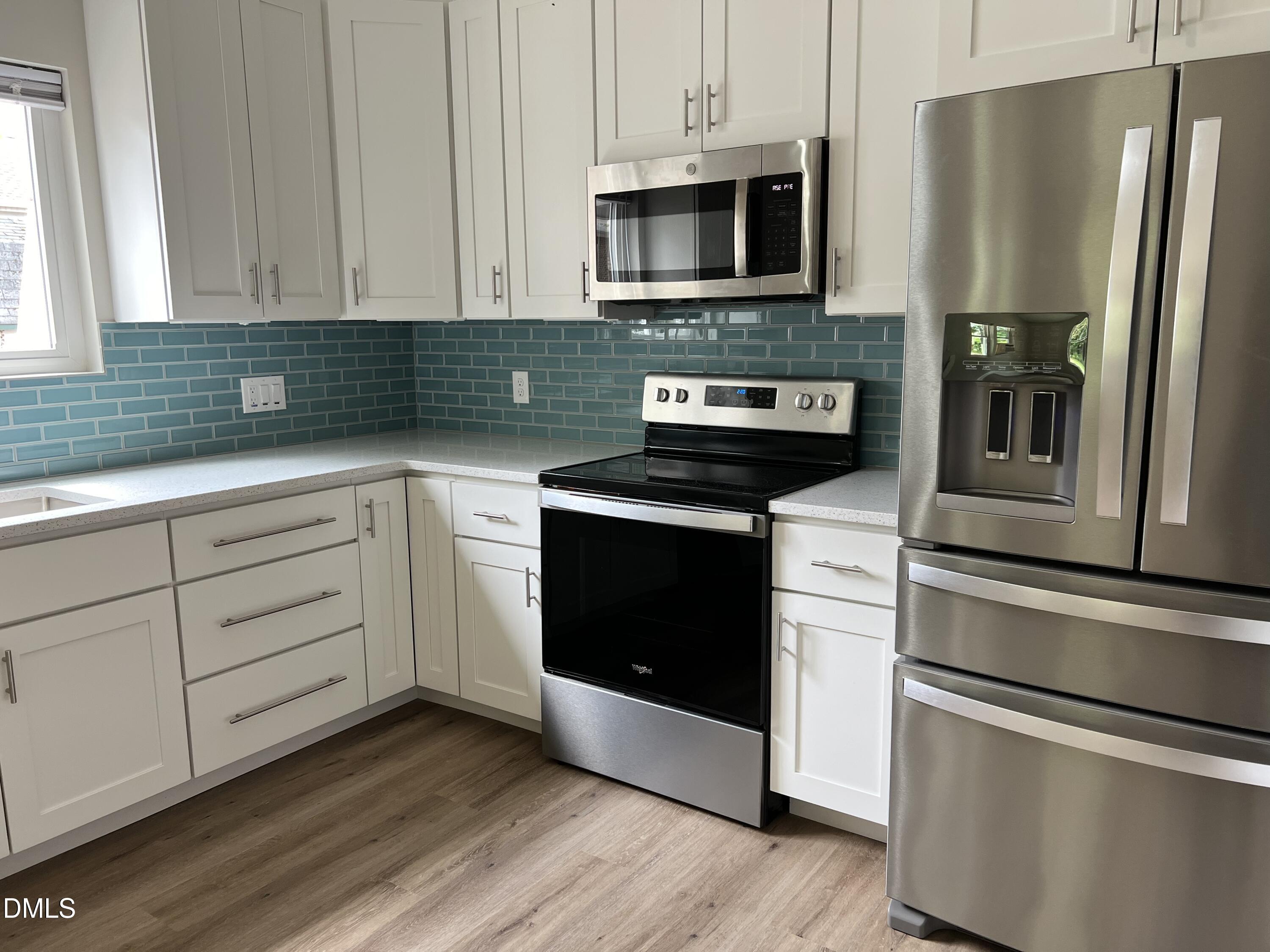 507 North Maple Street, Unit A Durham, NC 27703 - Photo 5 of 15 a kitchen with cabinets stainless steel appliances and wooden floor