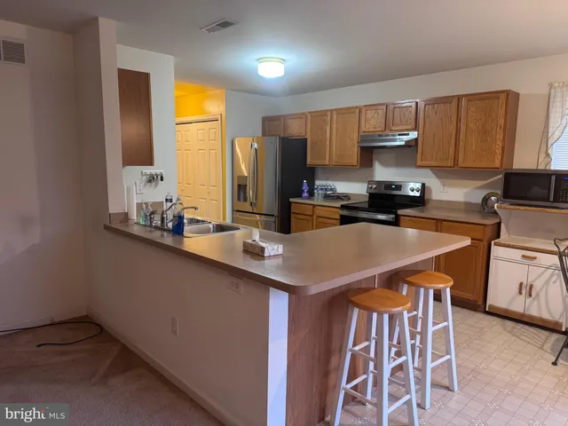 a kitchen with stainless steel appliances a sink a stove a refrigerator cabinets and a dining table