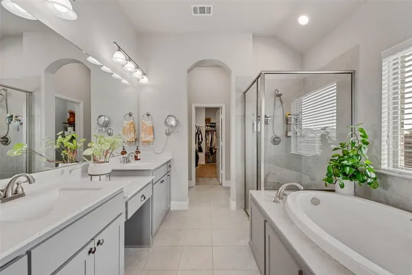 a spacious bathroom with a granite countertop tub a double vanity sink and a large mirror