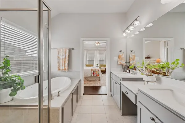 a spacious en suite bathroom with a granite countertop sink mirror and tub