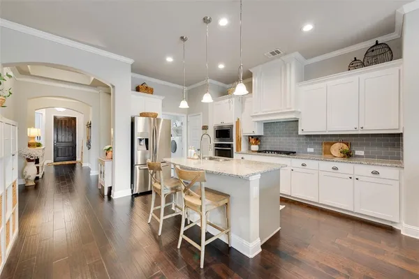a kitchen with white cabinets stainless steel appliances and wooden floor