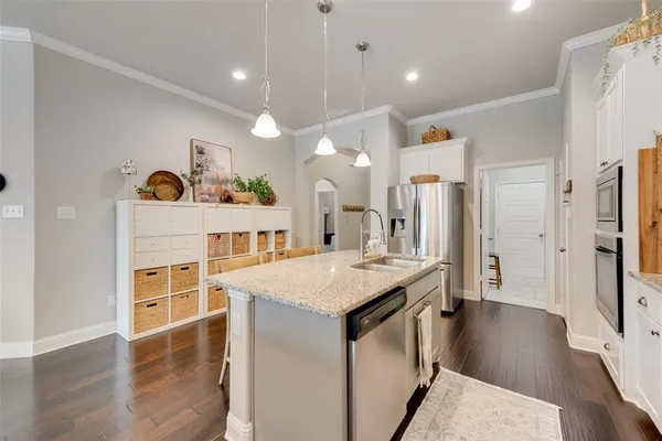 a open kitchen with a refrigerator a stove top oven a sink dishwasher and white cabinets with wooden floor