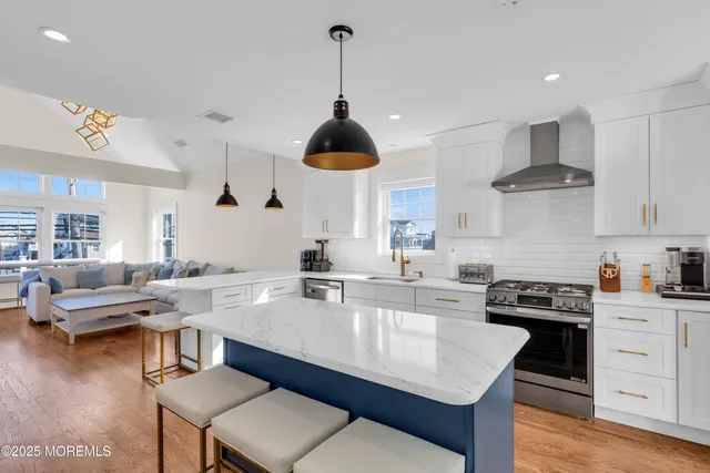 a kitchen with kitchen island granite countertop a stove a sink a dining table and chairs with wooden floor