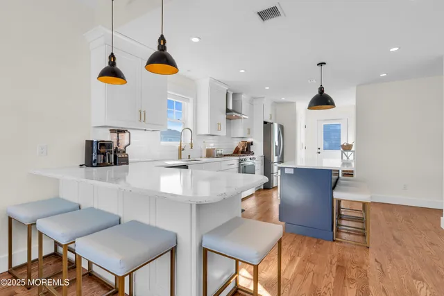 a kitchen with stainless steel appliances kitchen island granite countertop a sink a stove a refrigerator and island with wooden floor