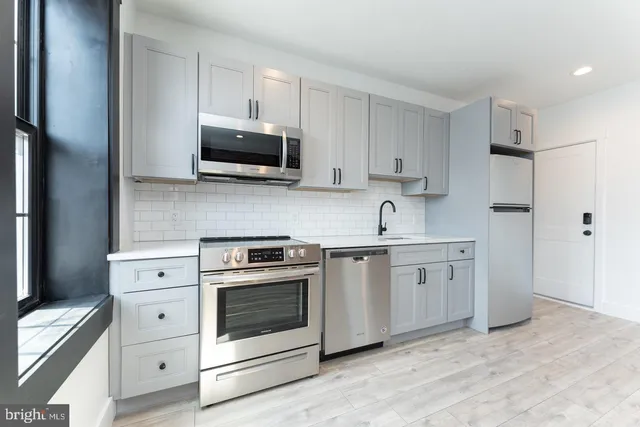 a kitchen with white cabinets stainless steel appliances and sink