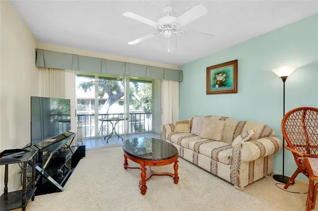 a living room with furniture ceiling fan and a large window