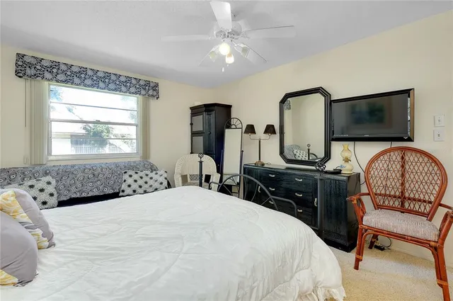 a bedroom with a bed a couch and a flat tv screen on dresser