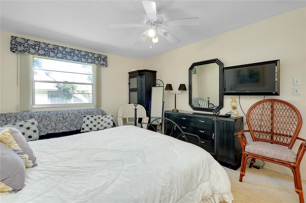 2280 Stickney Point Road, Unit 432 Sarasota, FL 34231 - Photo 17 of 35 a bedroom with a bed a couch and a flat tv screen on dresser