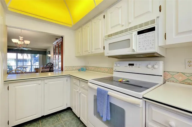 a kitchen with granite countertop white cabinets and white appliances