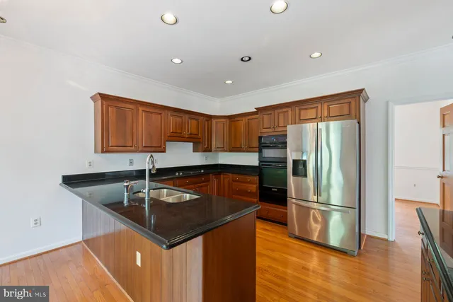 a kitchen with stainless steel appliances granite countertop wooden cabinets a sink and dishwasher with wooden floor