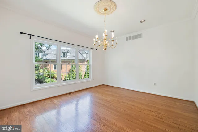 a view of a hallway with wooden floor and a chandelier