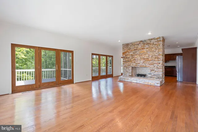 a view of an empty room with wooden floor and a fireplace