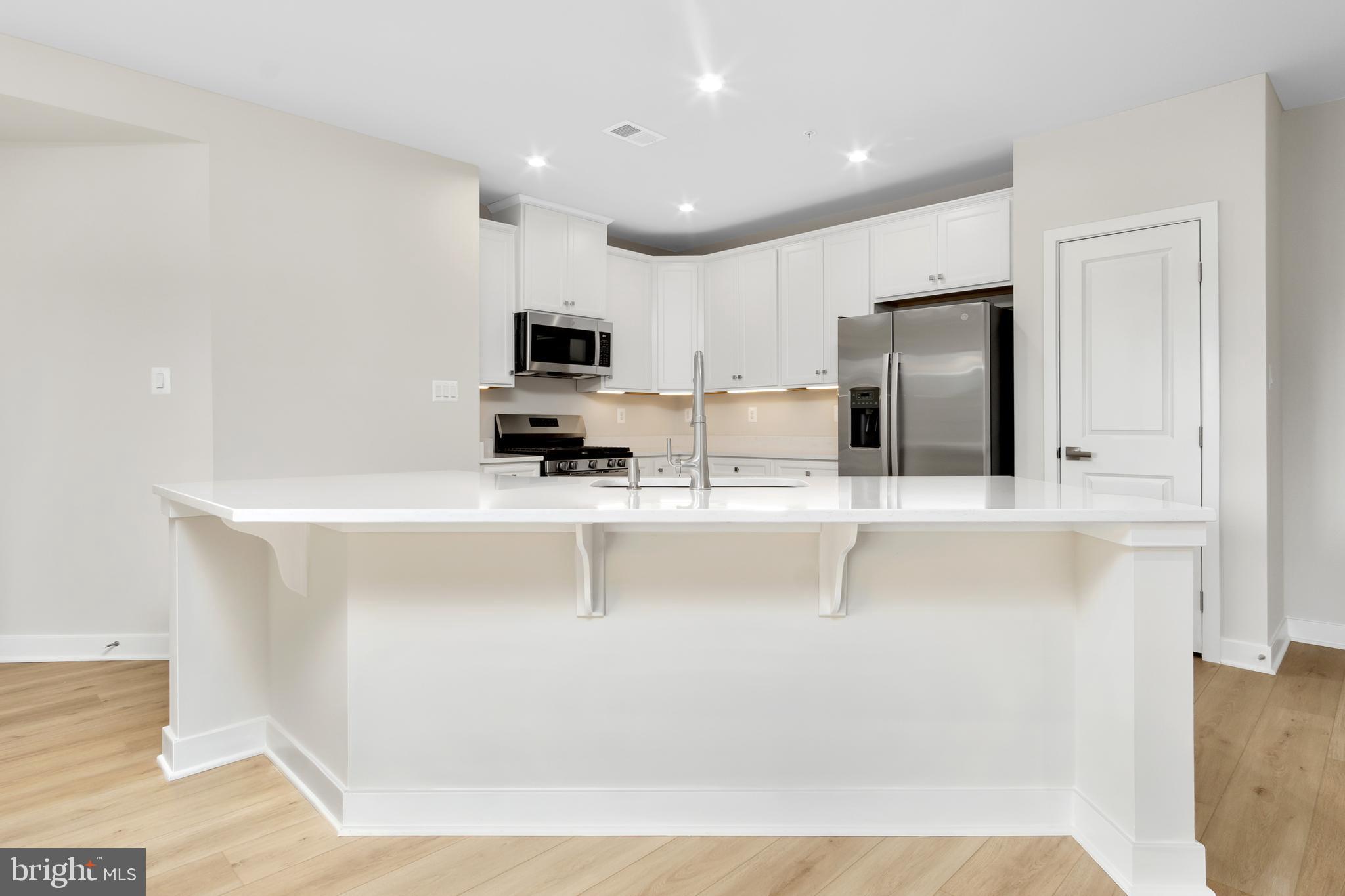 9935 Sofield Place, Unit 201 Frederick, MD 21701 - Photo 11 of 39 a kitchen with kitchen island white cabinets and stainless steel appliances