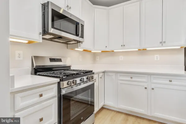 a kitchen with stainless steel appliances granite countertop white cabinets a stove top oven