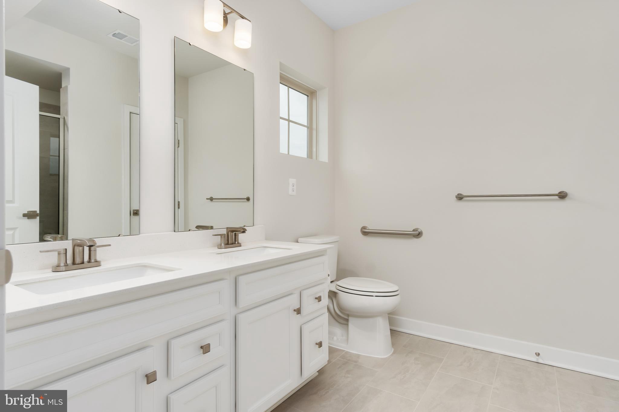 9935 Sofield Place, Unit 201 Frederick, MD 21701 - Photo 27 of 39 a bathroom with a double vanity sink toilet and a mirror