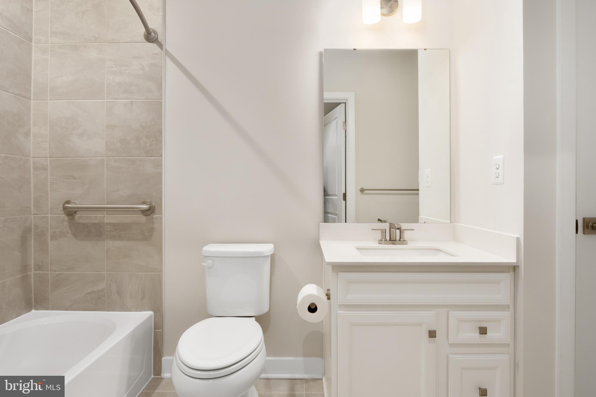 9935 Sofield Place, Unit 201 Frederick, MD 21701 - Photo 32 of 39 a bathroom with a toilet a sink a mirror a bathtub and vanity