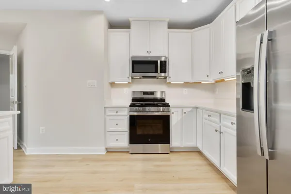 a kitchen with white cabinets and stainless steel appliances