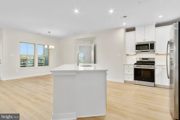 a open kitchen with stainless steel appliances a stove top oven a sink dishwasher and a refrigerator with wooden floor