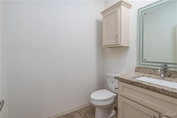 a bathroom with a granite countertop toilet and sink