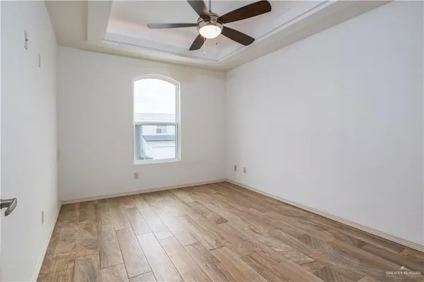 an empty room with wooden floor chandelier fan and windows